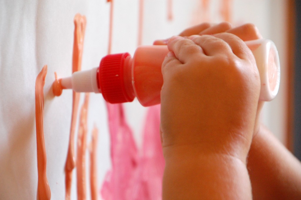 child squeezing paint